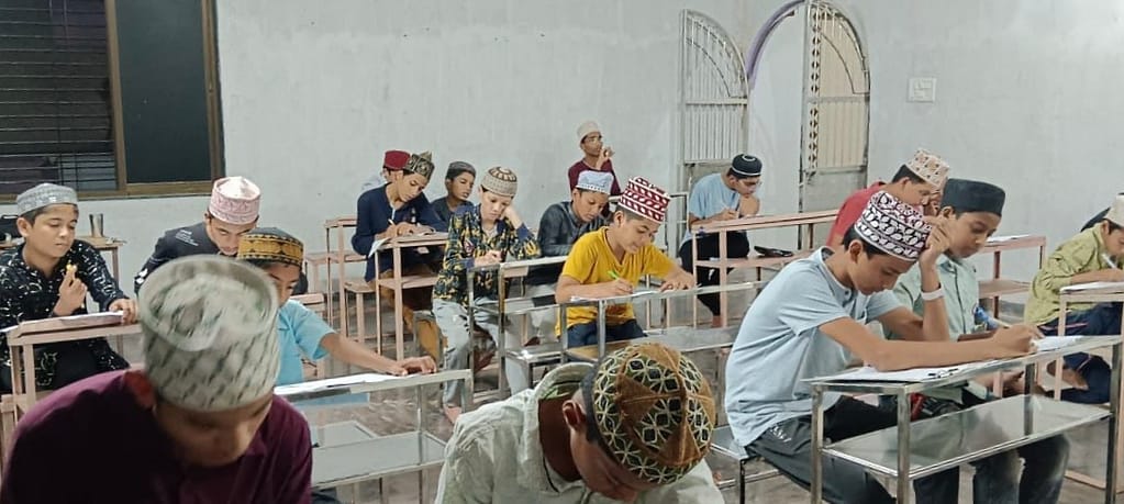 IMG_20250828_214828 - NewsNation Online छात्र कक्षा में पांच वर्षीय आलिम कोर्स के इम्तिहान में भाग लेते हुए, जिसमें वे ध्यान से प्रश्न पत्र हल कर रहे हैं।