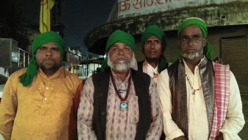WhatsApp Image 2026-02-24 at 191451 1 - NewsNation Online Four men wearing green headscarves and traditional attire standing together at night in front of a building.